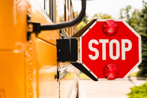 Close up yellow school bus. Stop sign. Be careful, schoolchildren crossing the road. New academic year semester. Welcome back to school. Lockdown, distance remote education learning