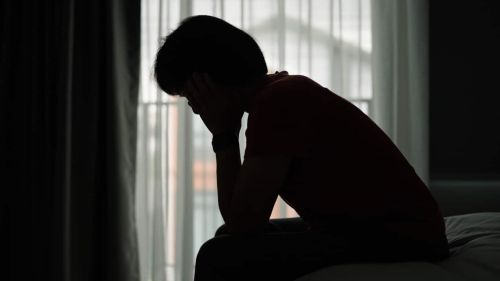 Woman depressed while sitting on bed during day time.